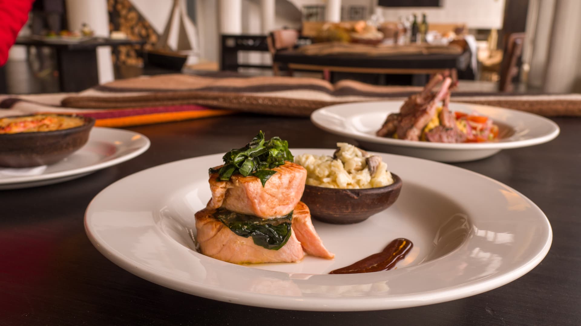 Salmon with greens and risotto in a bowl on a white plate at a restaurant in Southern Chile.