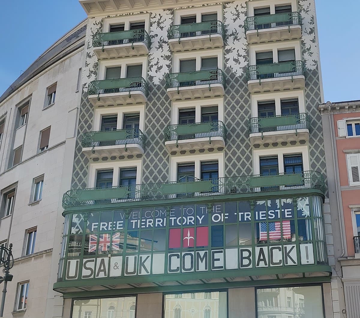 Historic building with balconies and large sign reading "Welcome to the Free Territory of Trieste